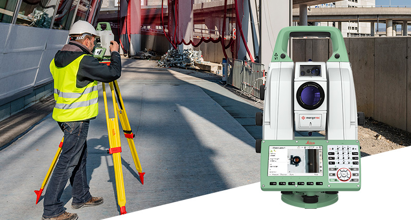 Surveyor measures with a robotic total station on a road infrastructure construction site.